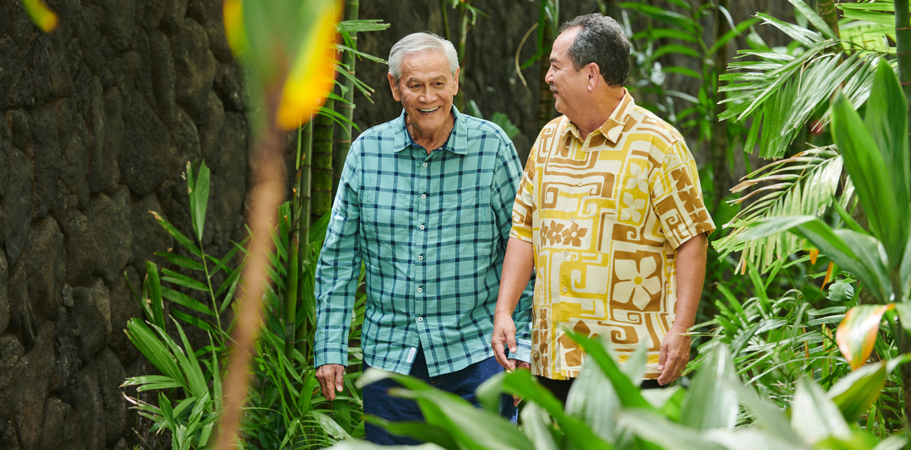 Two men walking along a garden path at The Plaza Assisted Living.