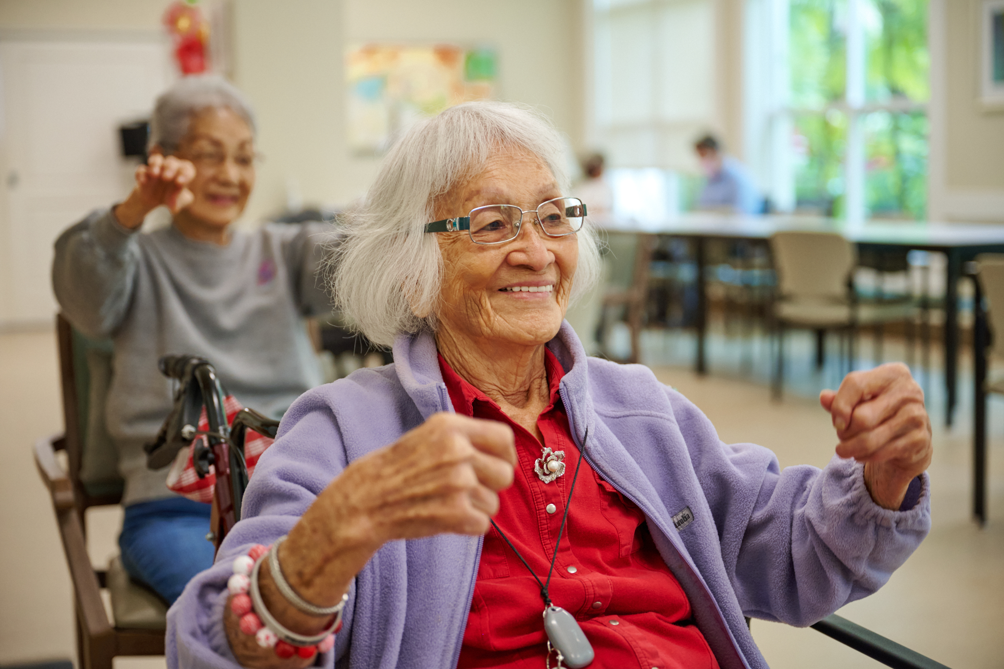 Smiling resident participating in a group wellness class at The Plaza Assisted Living.