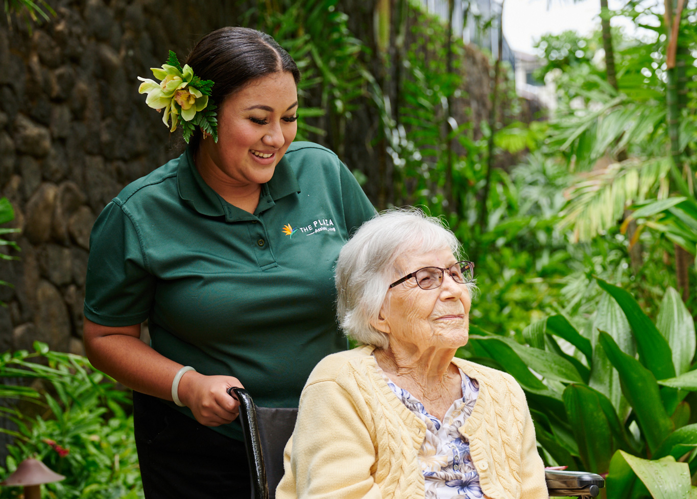 Staff member smiling while pushing a resident in a wheelchair.