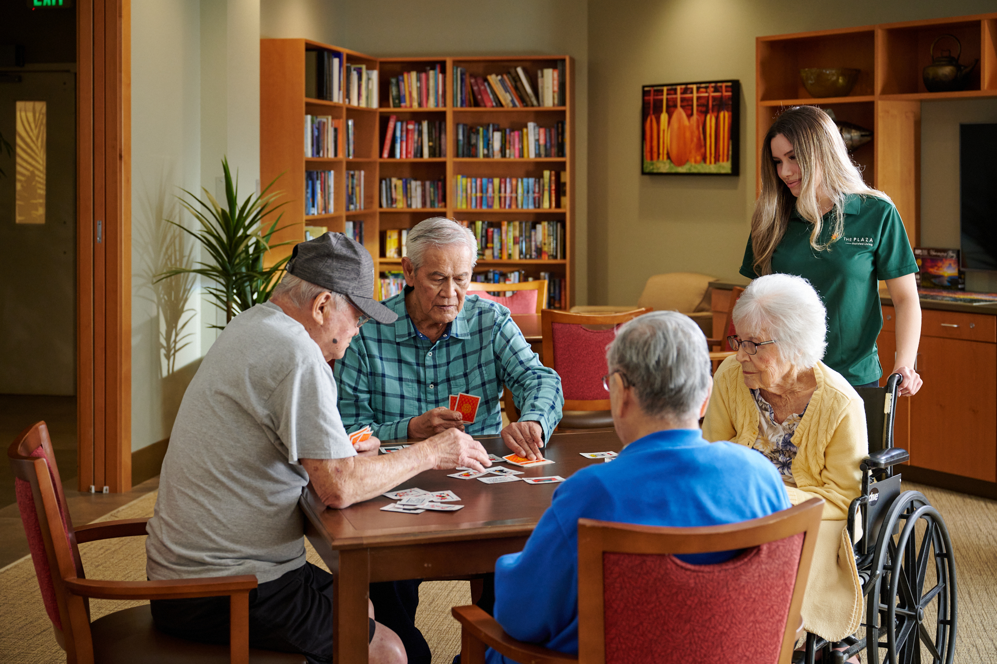 Residents playing a card game in a comfortable lounge at Plaza Assisted Living.
