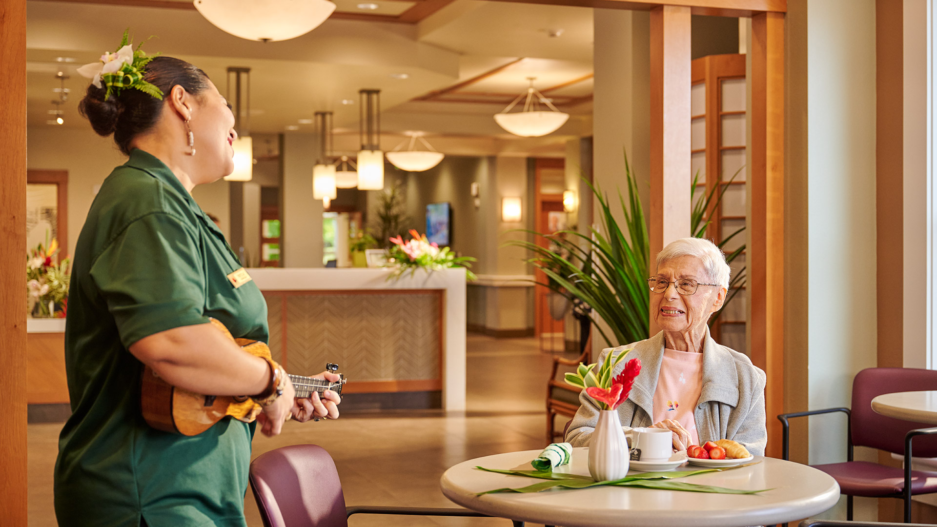 Staff playing ukulele for a resident at plaza assisted living.