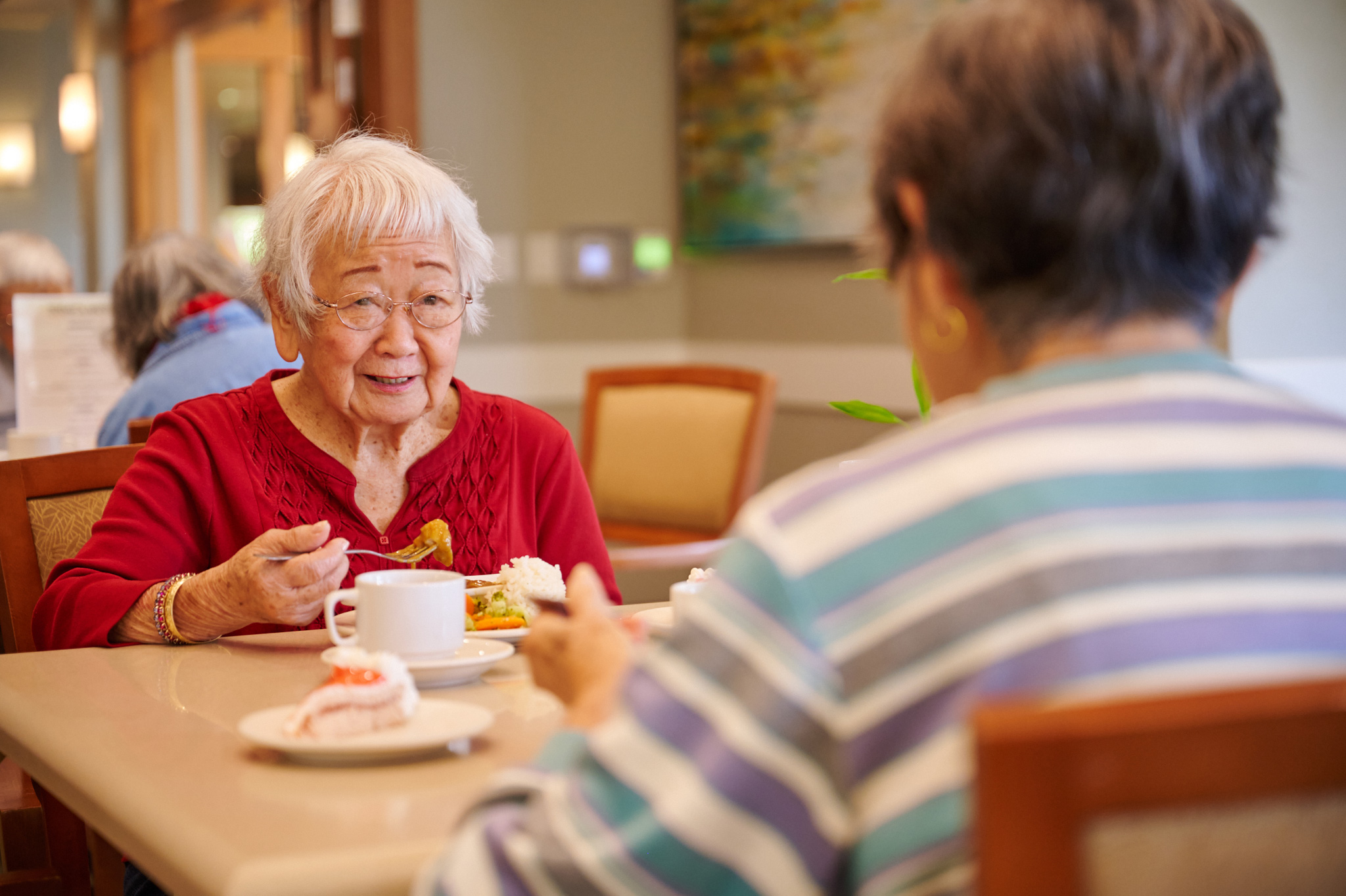 Two residents sharing a meal at an assisted living facility with memory care.