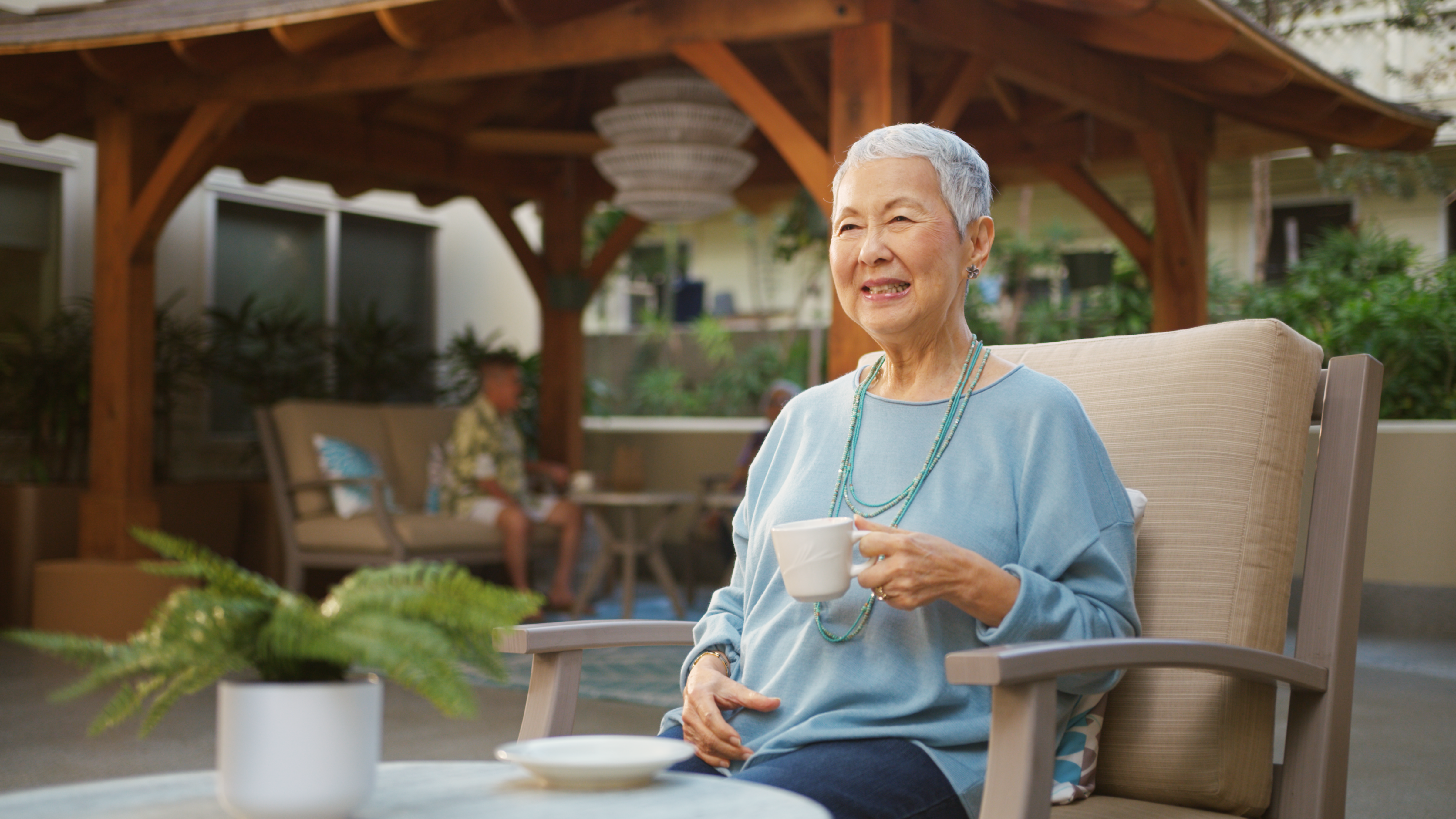 Resident enjoying coffee in an outdoor pavilion at The Plaza Assisted Living.