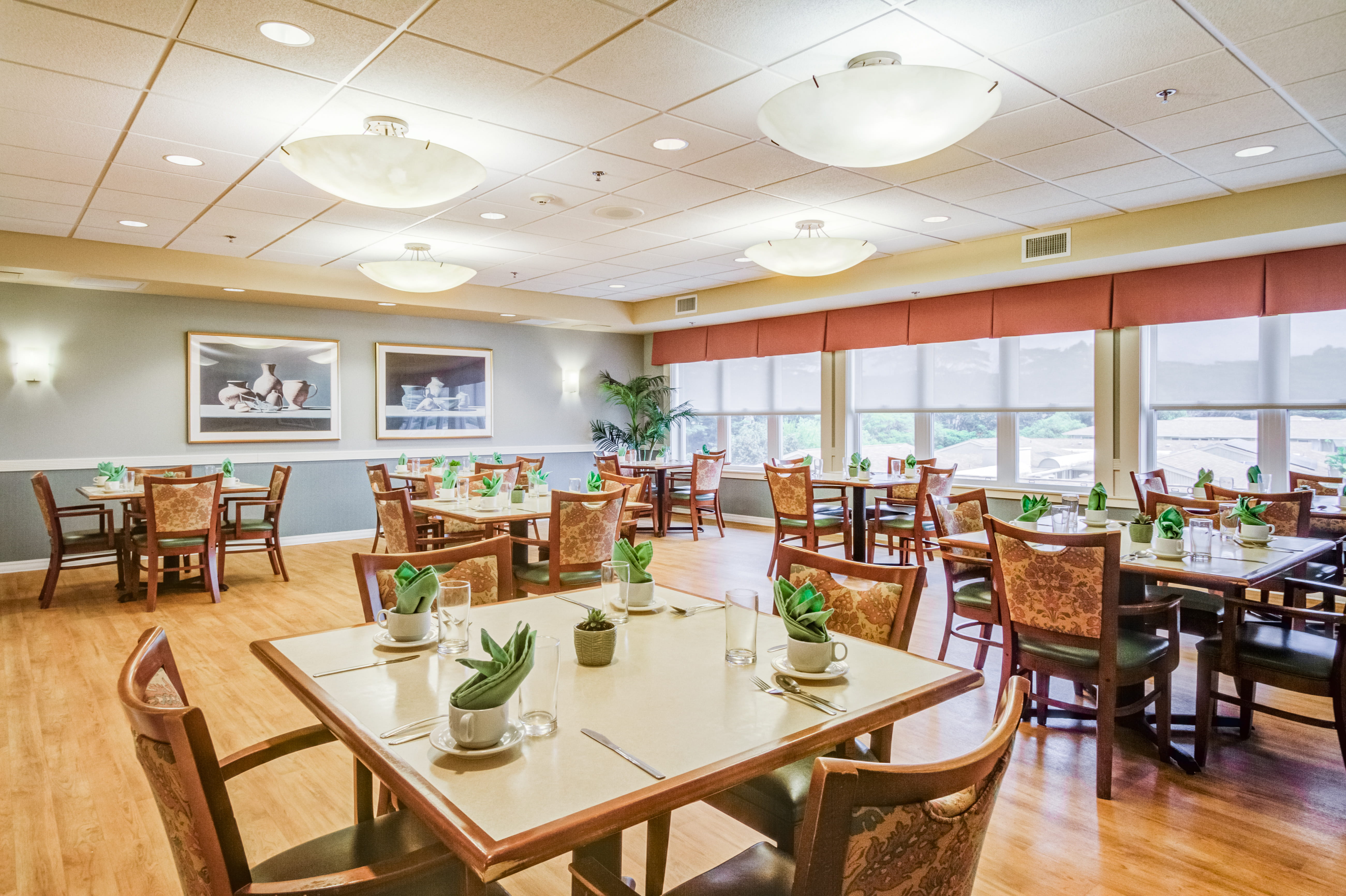 Dining room set for a meal with large windows at The Plaza Assisted Living.