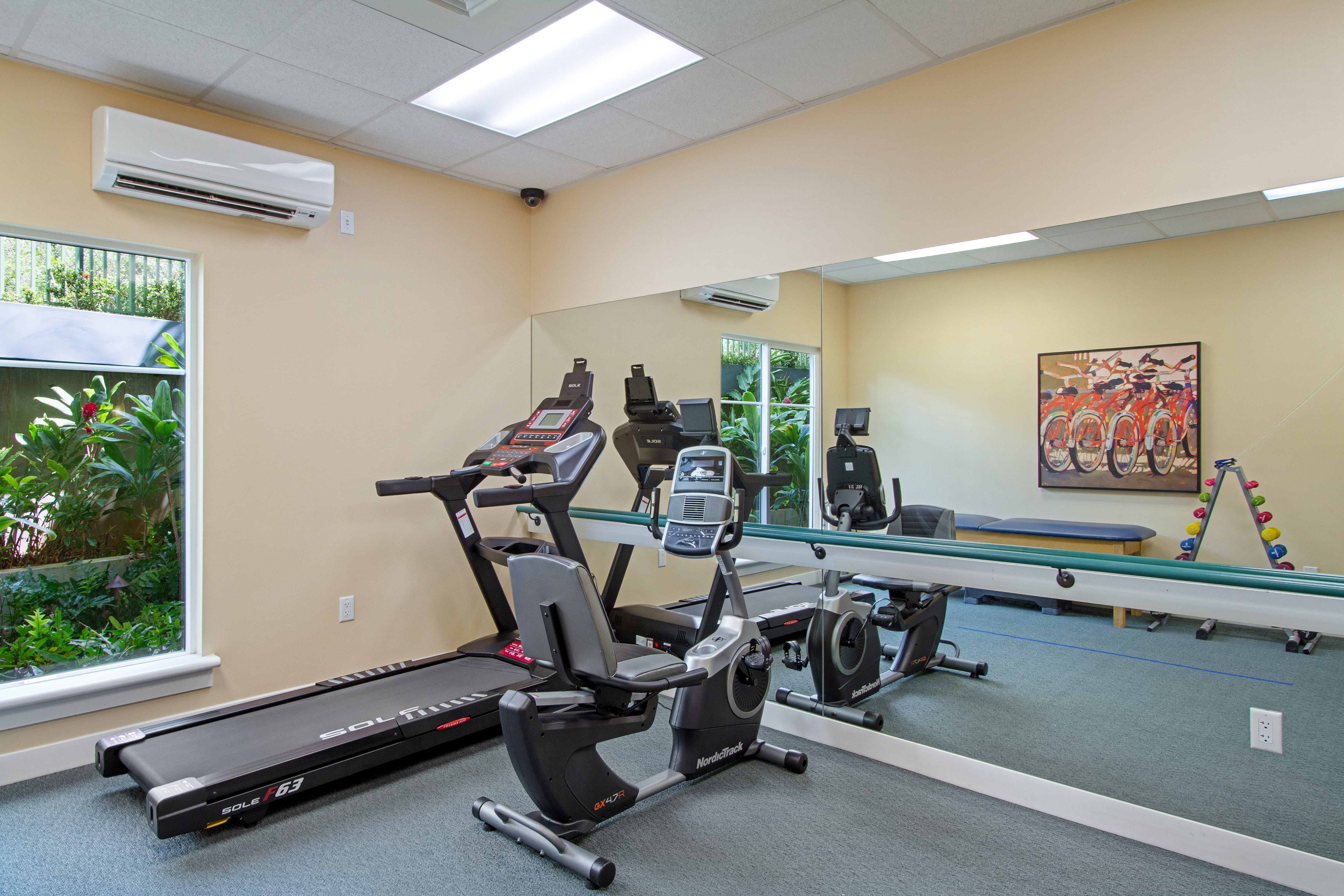 Modern exercise room at The Plaza Assisted Living Moanalua with a treadmill and stationary bike.
