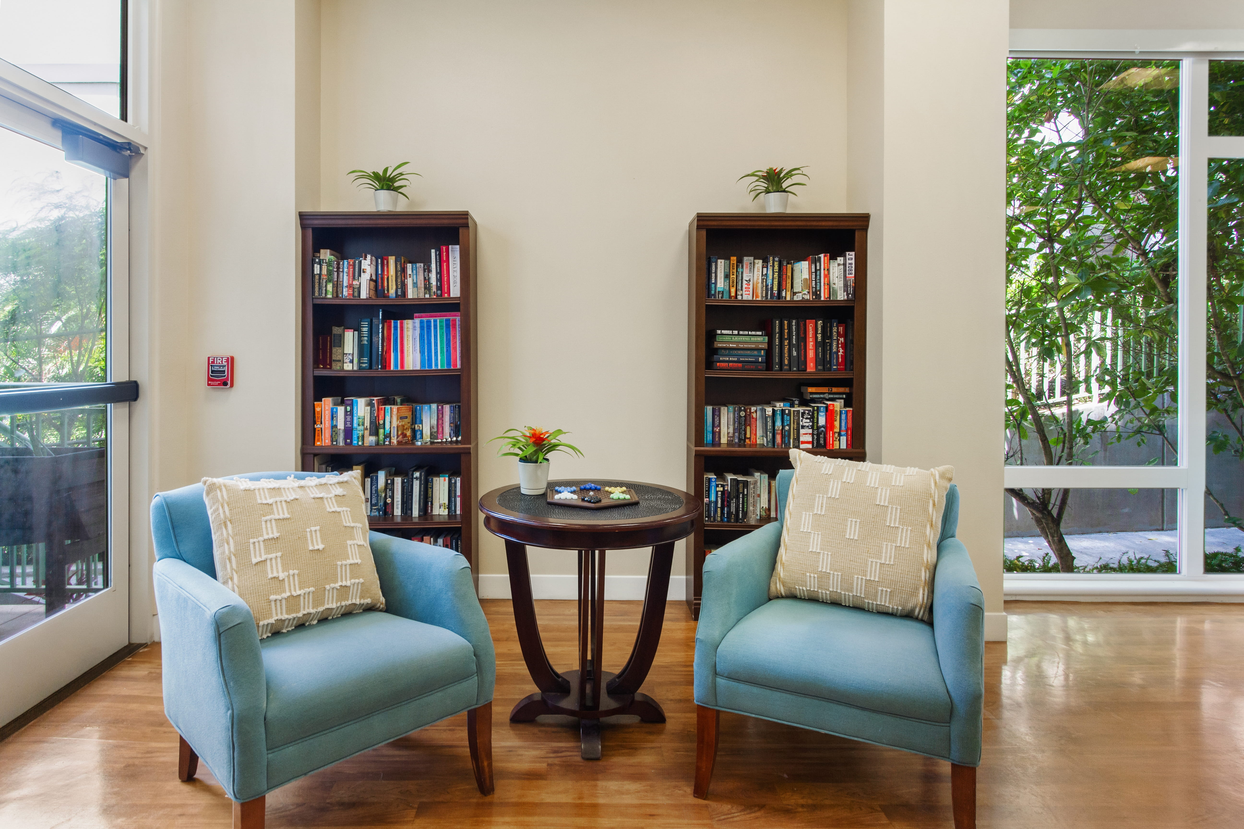 Blue armchairs and a game table in a library nook at The Plaza Assisted Living.