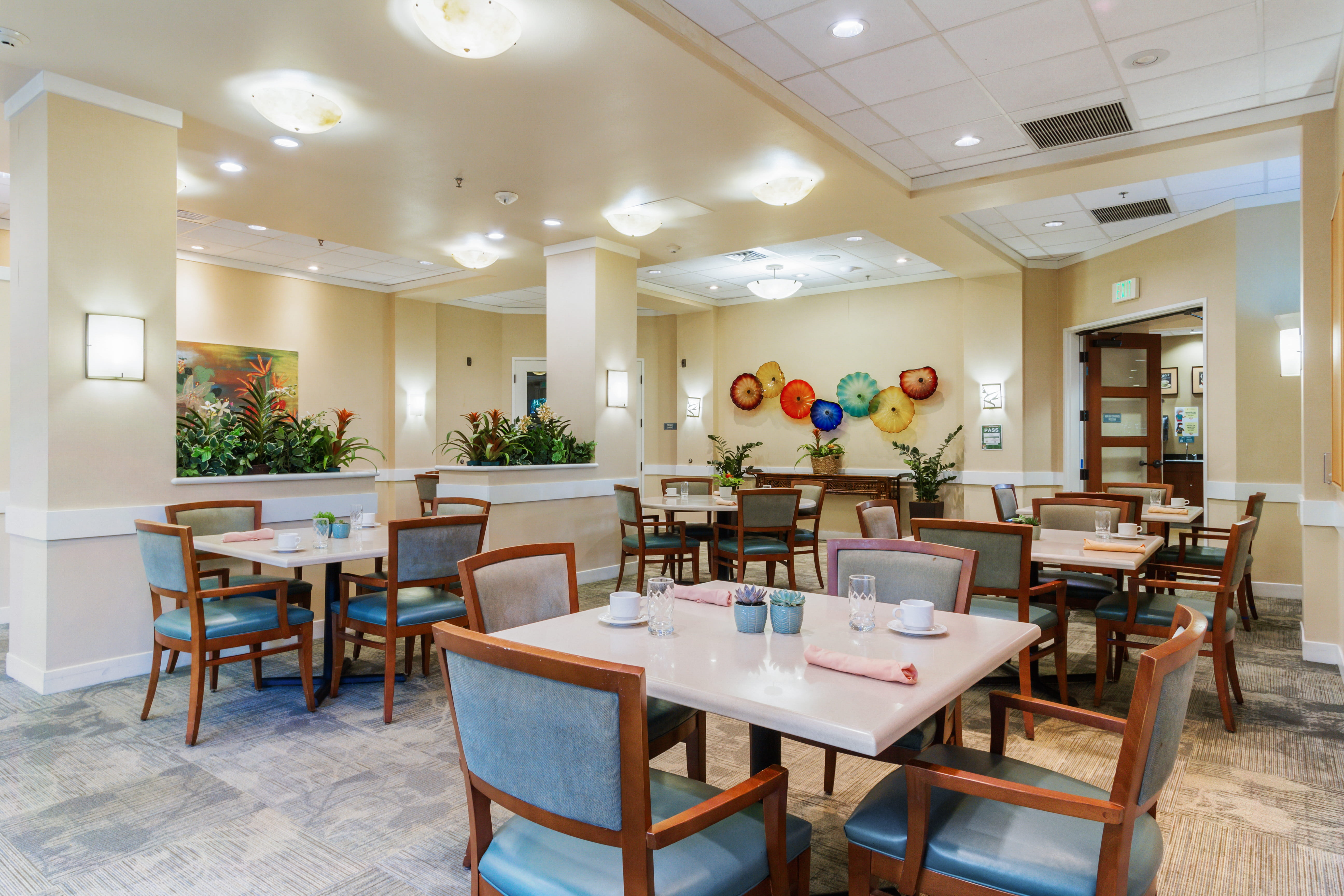 Elegant dining room at The Plaza Assisted Living Moanalua with modern tables and wall art.