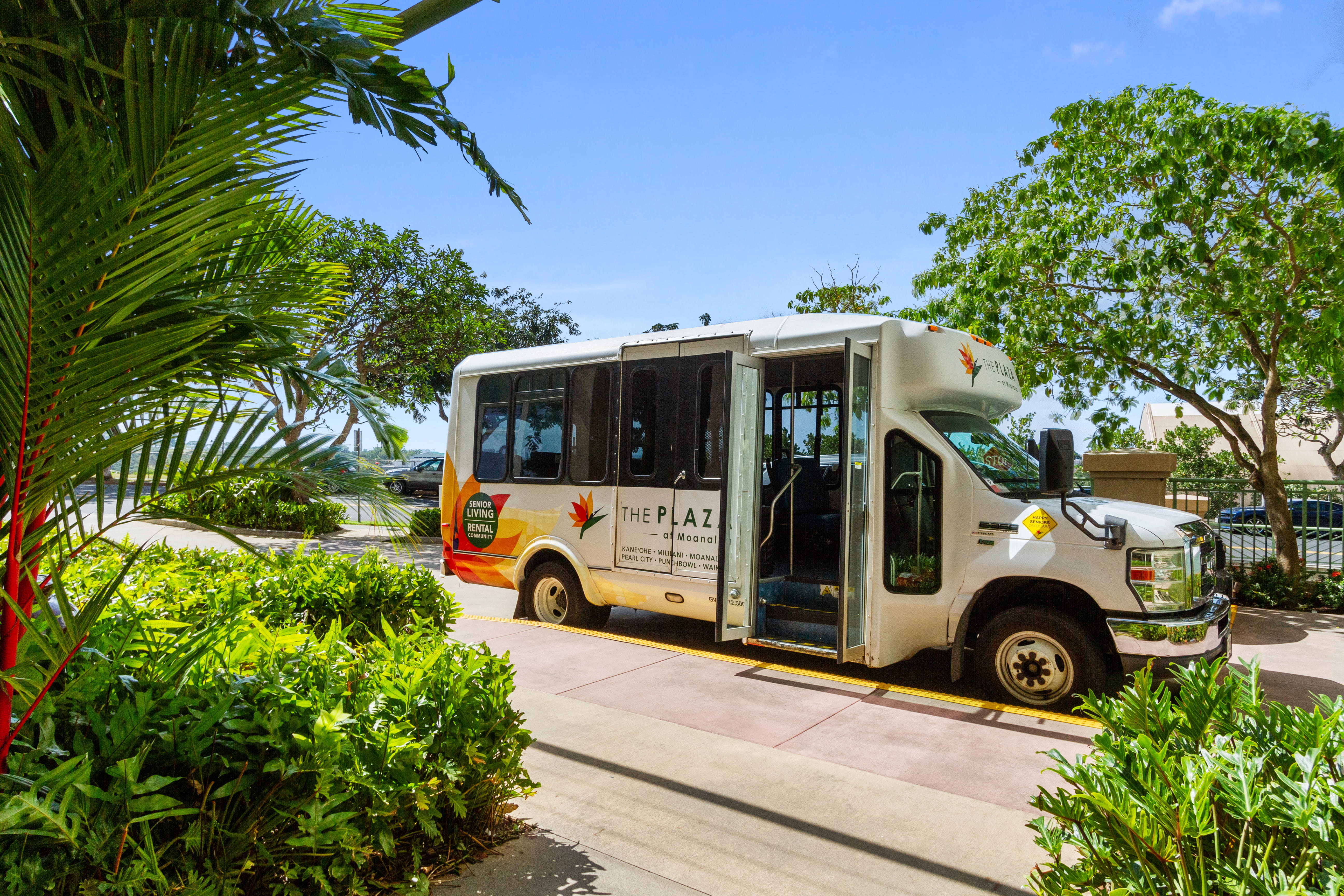 White resident shuttle bus parked in front of The Plaza Assisted Living Moanalua.
