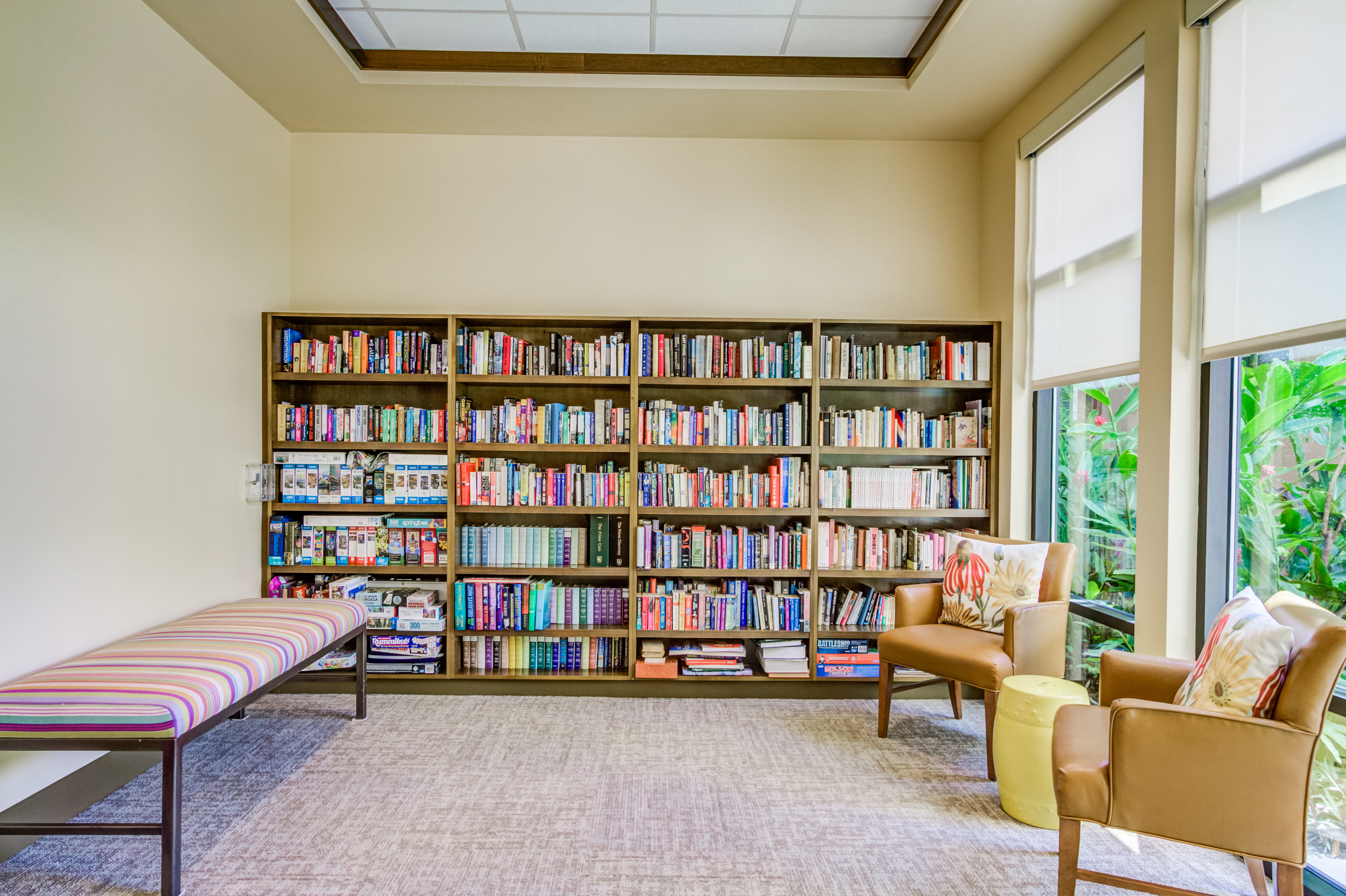 Quiet library at The Plaza Assisted Living with comfortable seating and stocked bookshelves.