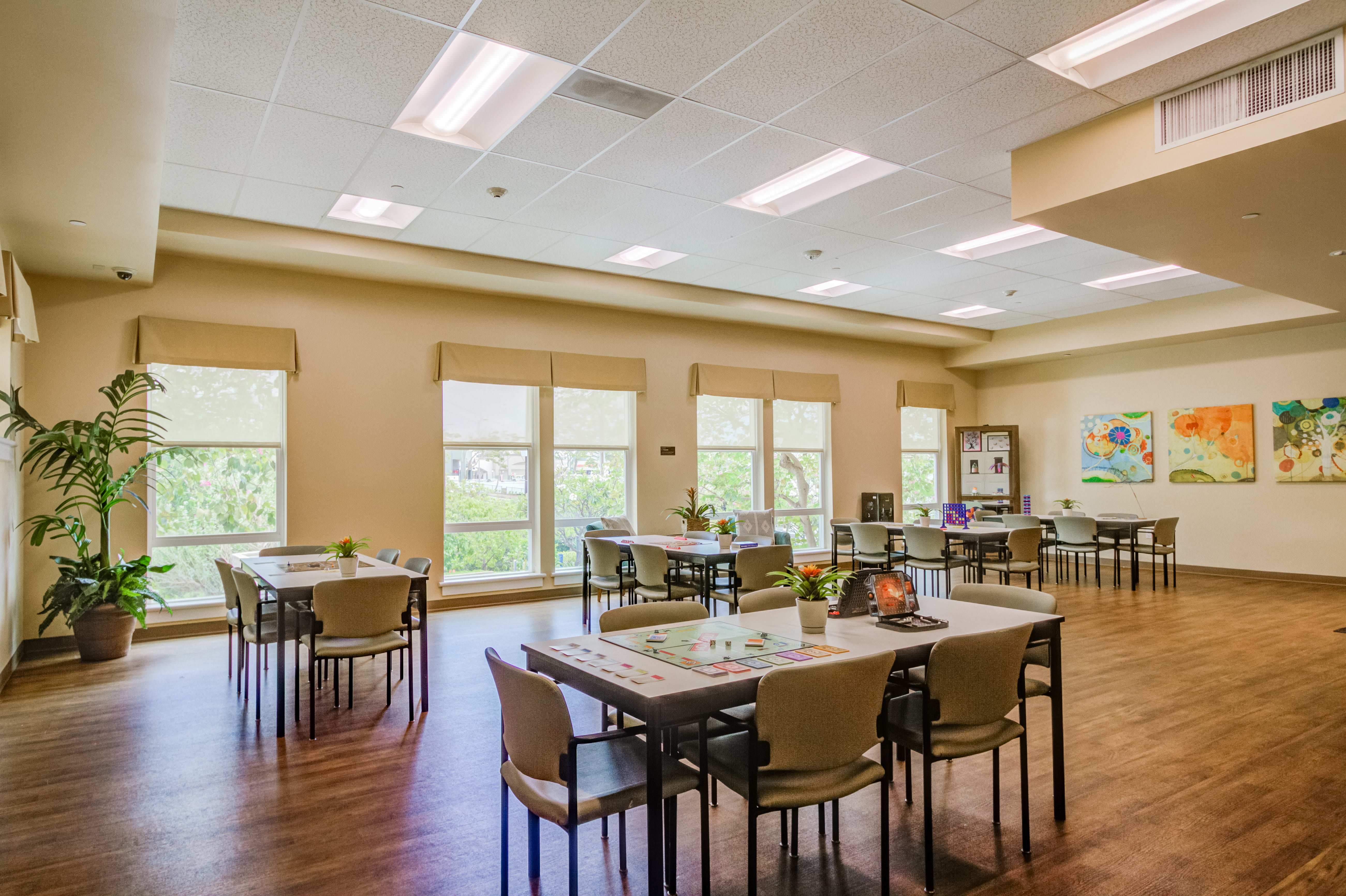 Large multipurpose activity room with board games and art at The Plaza Assisted Living.
