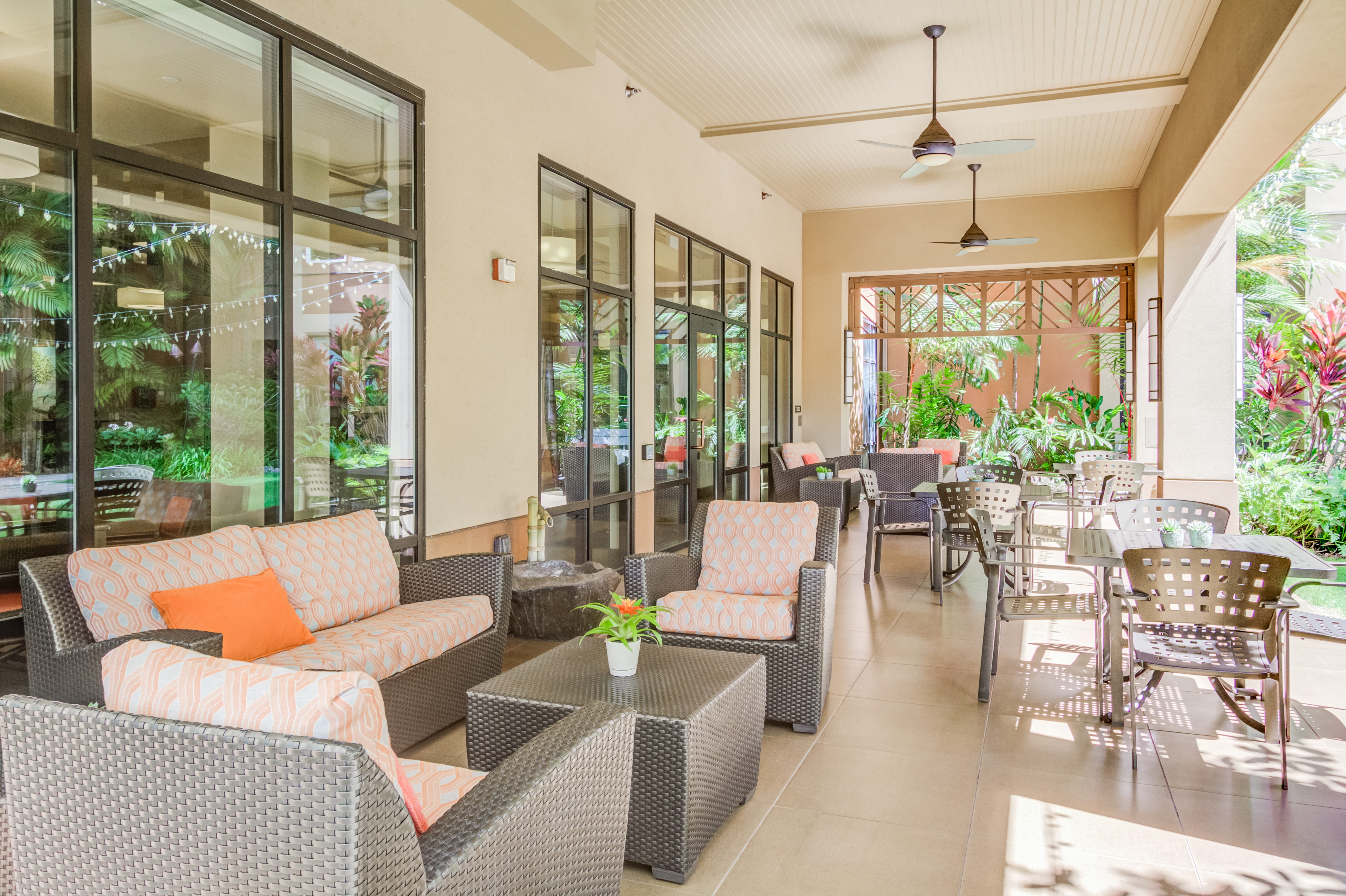 Covered outdoor lanai with wicker furniture at The Plaza Assisted Living.