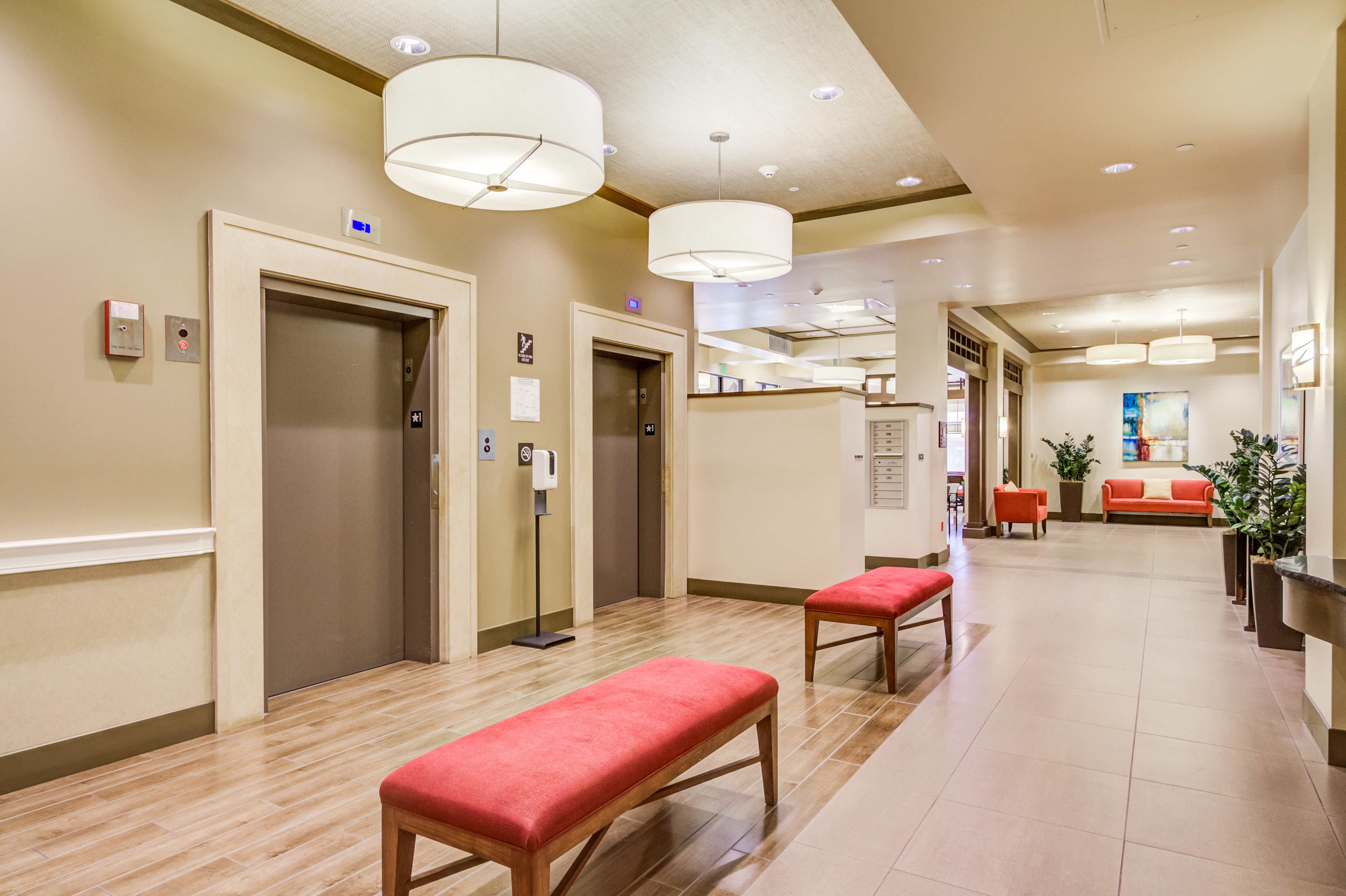 Modern elevator lobby with red benches and warm lighting at The Plaza Assisted Living.
