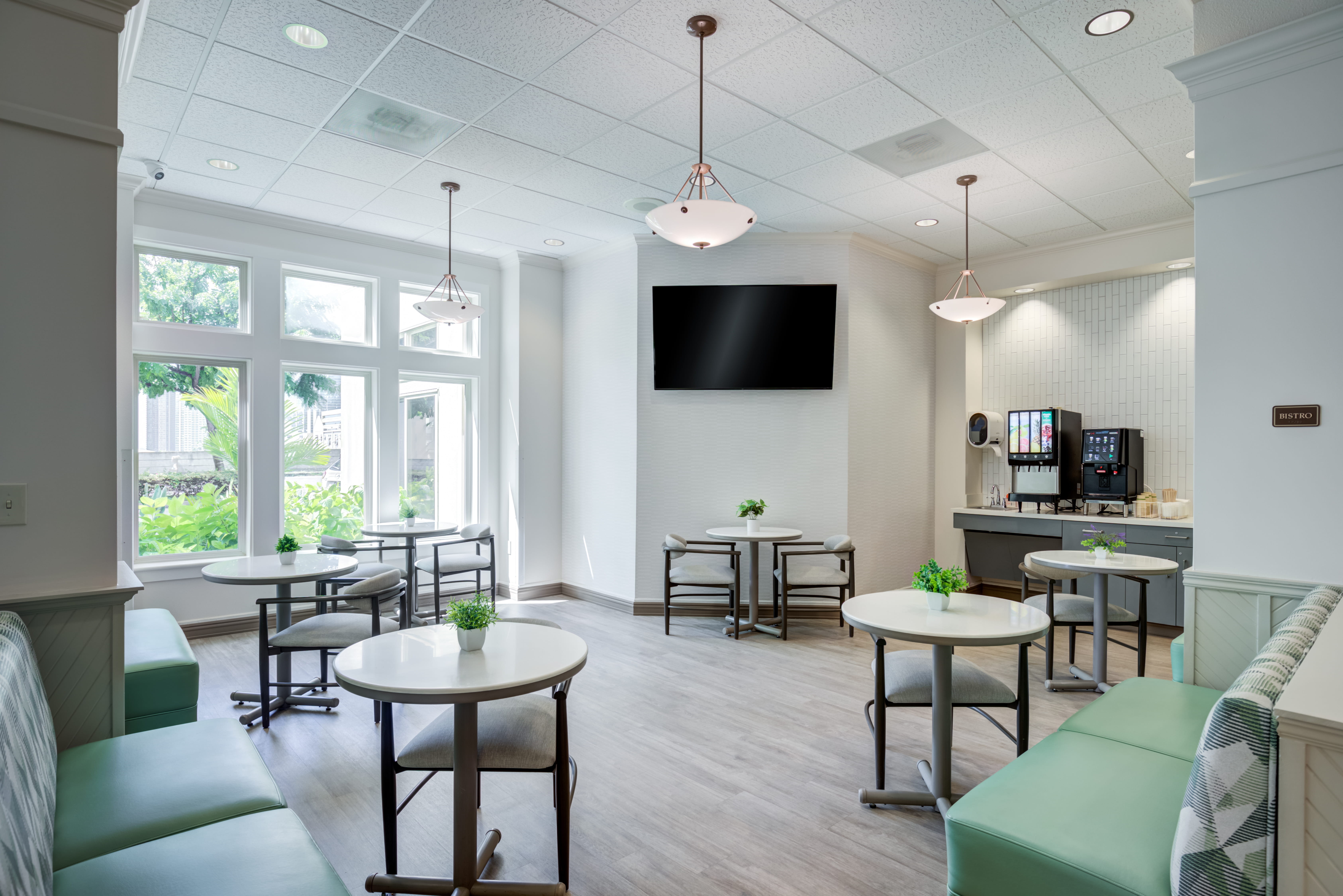Sunlit bistro with round tables and a beverage station.