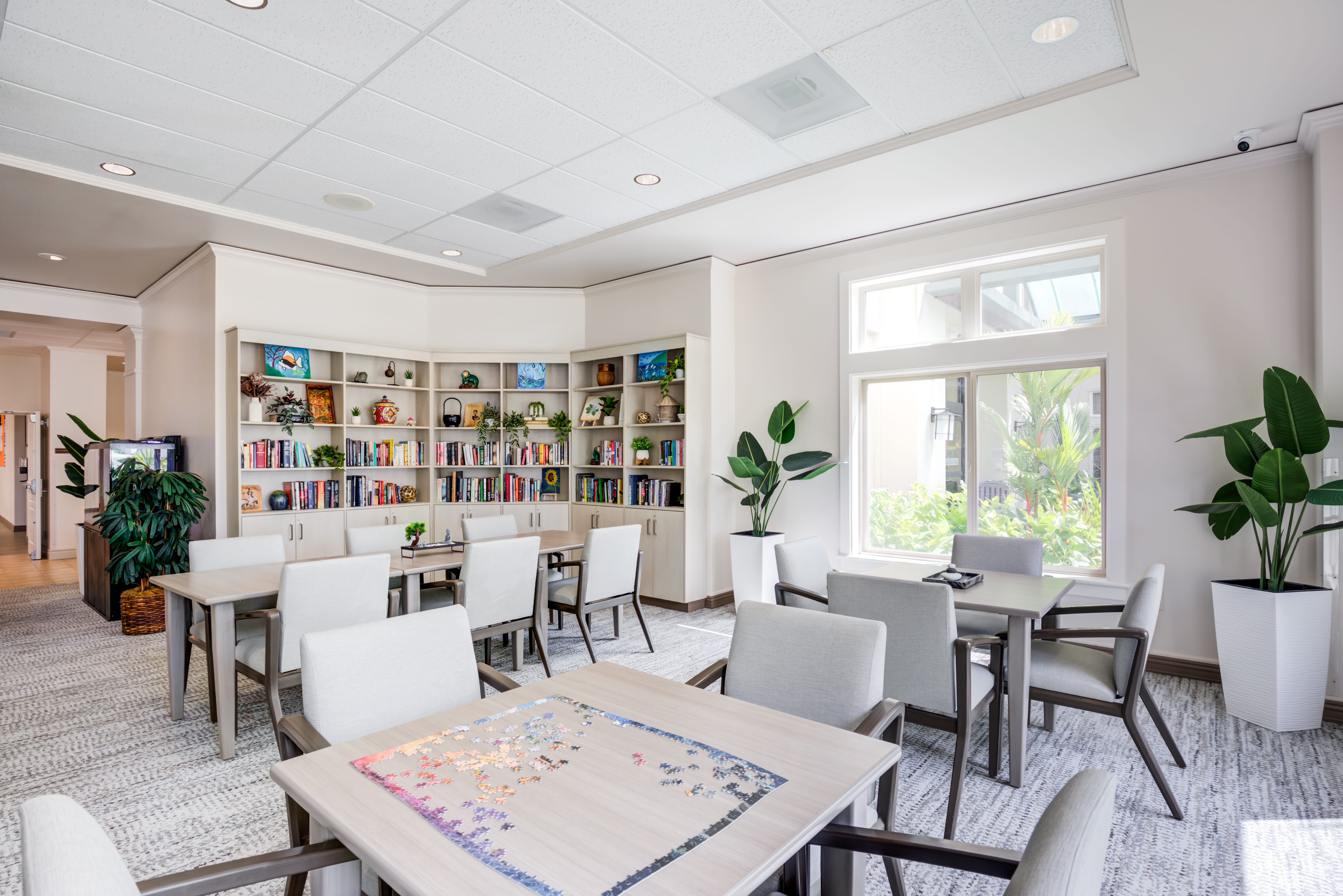 Resident library and activity room with tables and bookshelves.