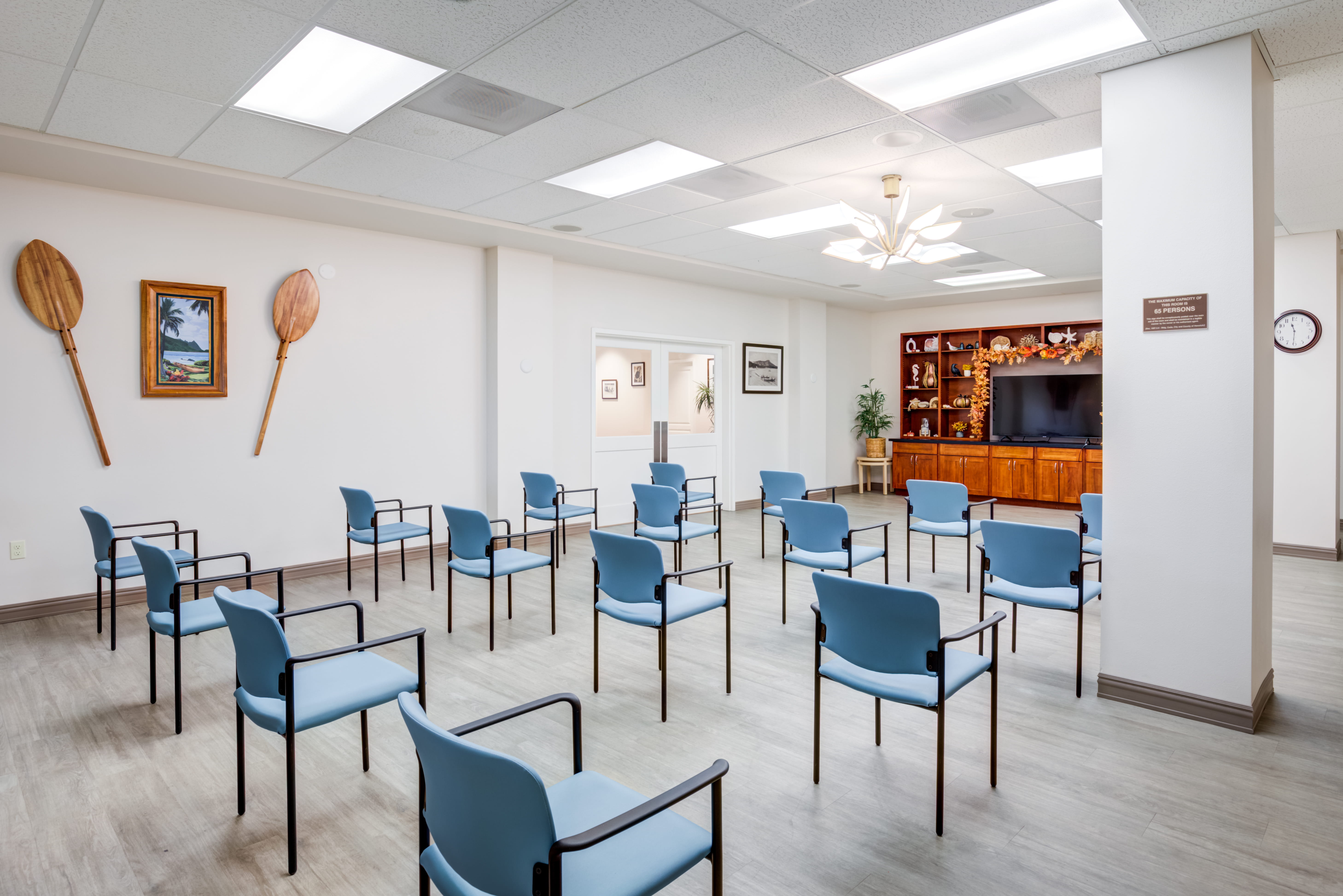 Media room with blue chairs and tropical decor at an assisted living facility.