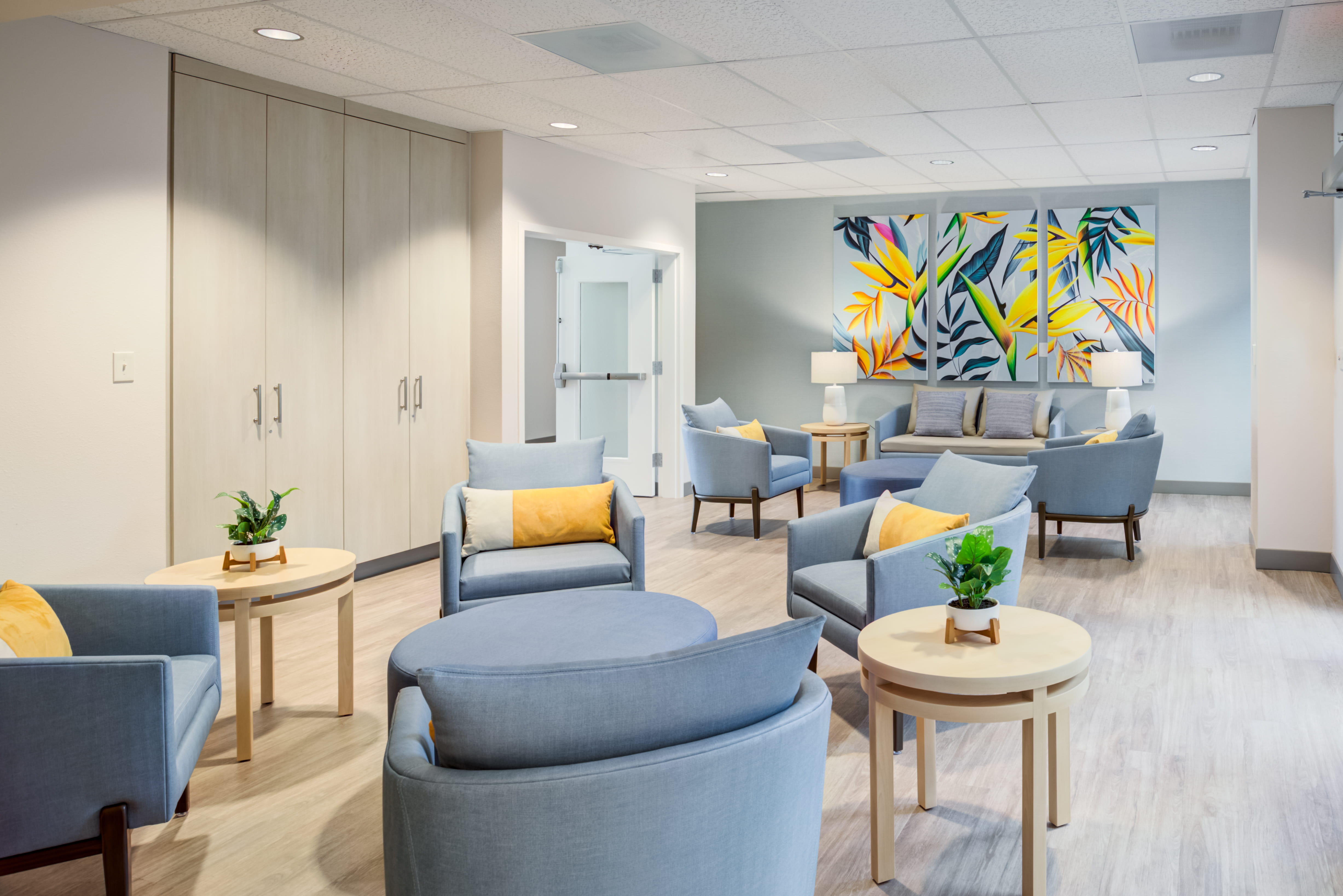 Modern lounge with blue chairs and floral art at a local senior living facility.