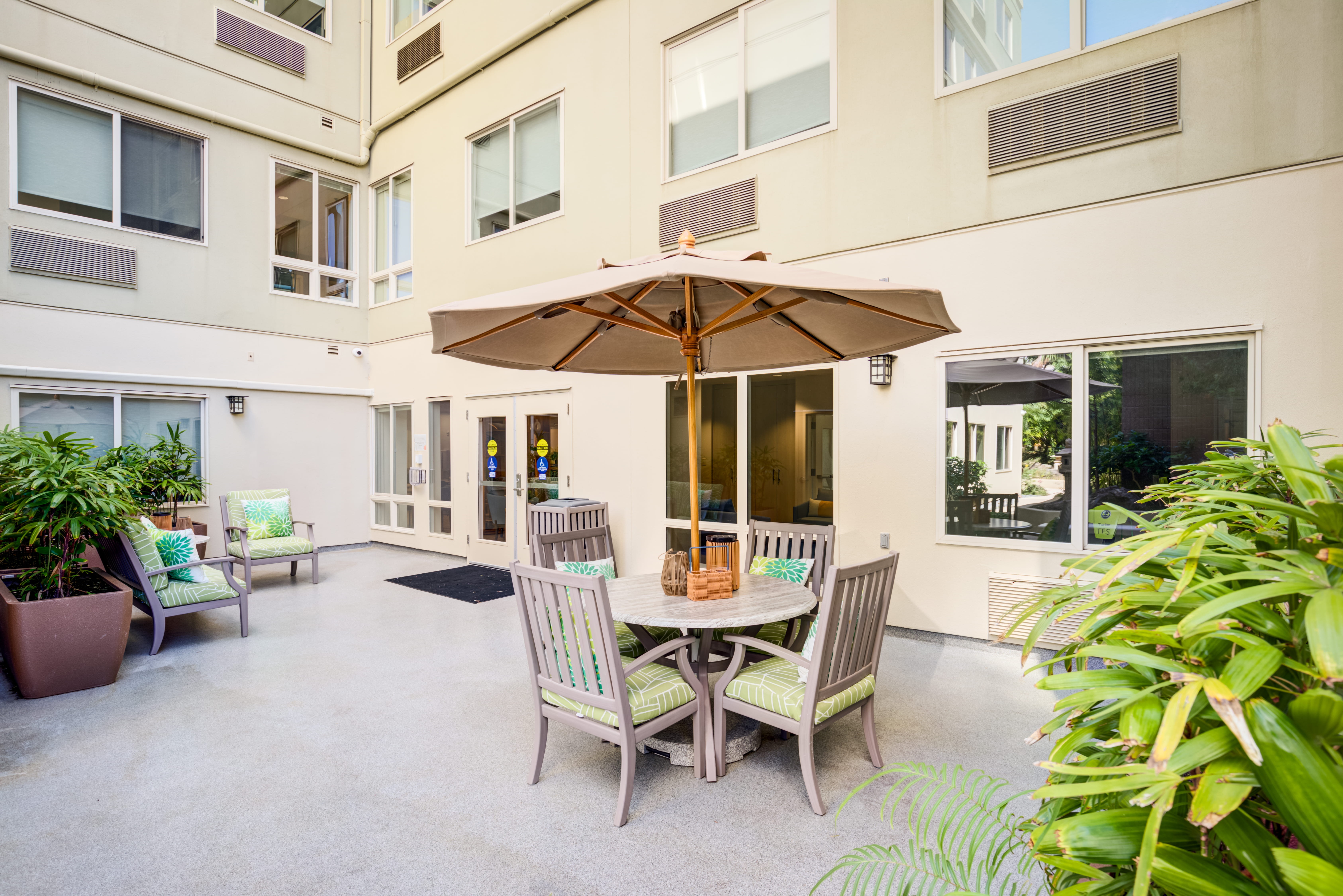 Outdoor courtyard with an umbrella table and potted plants.