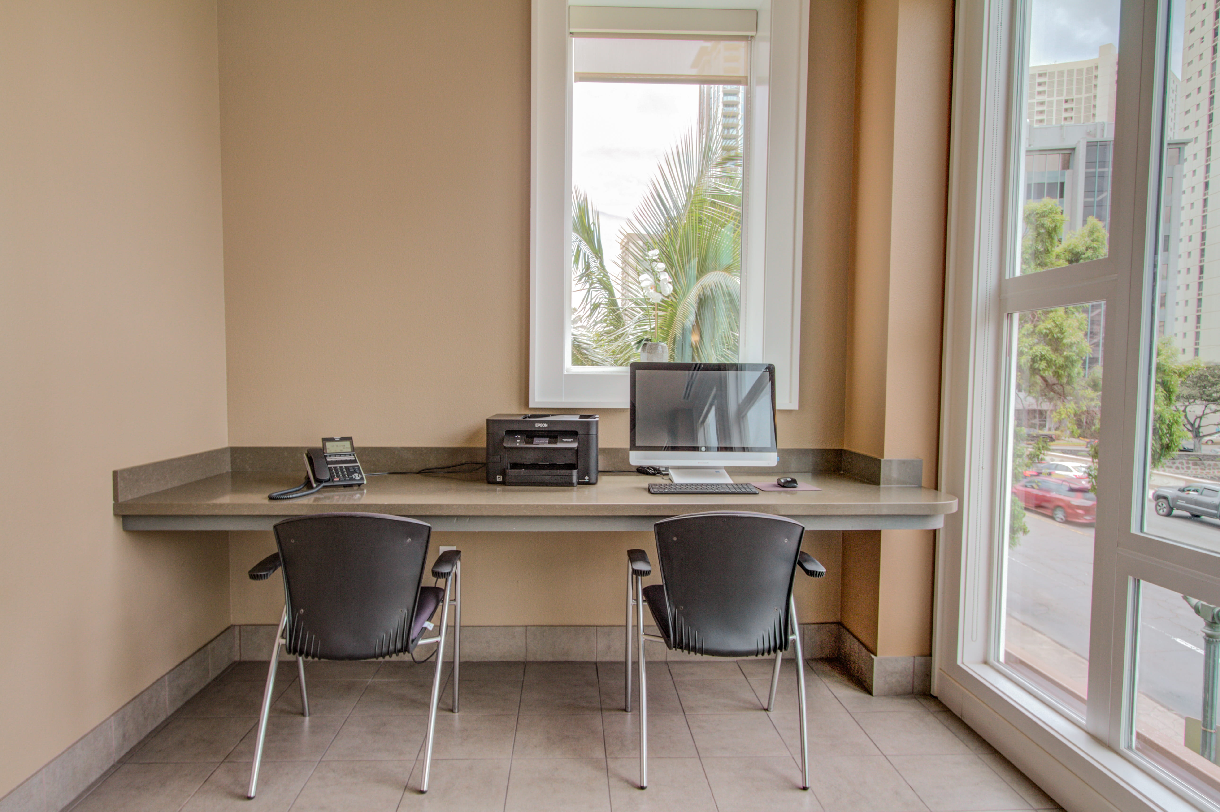 Business center with computers overlooking palm trees at The Plaza at Waikiki.