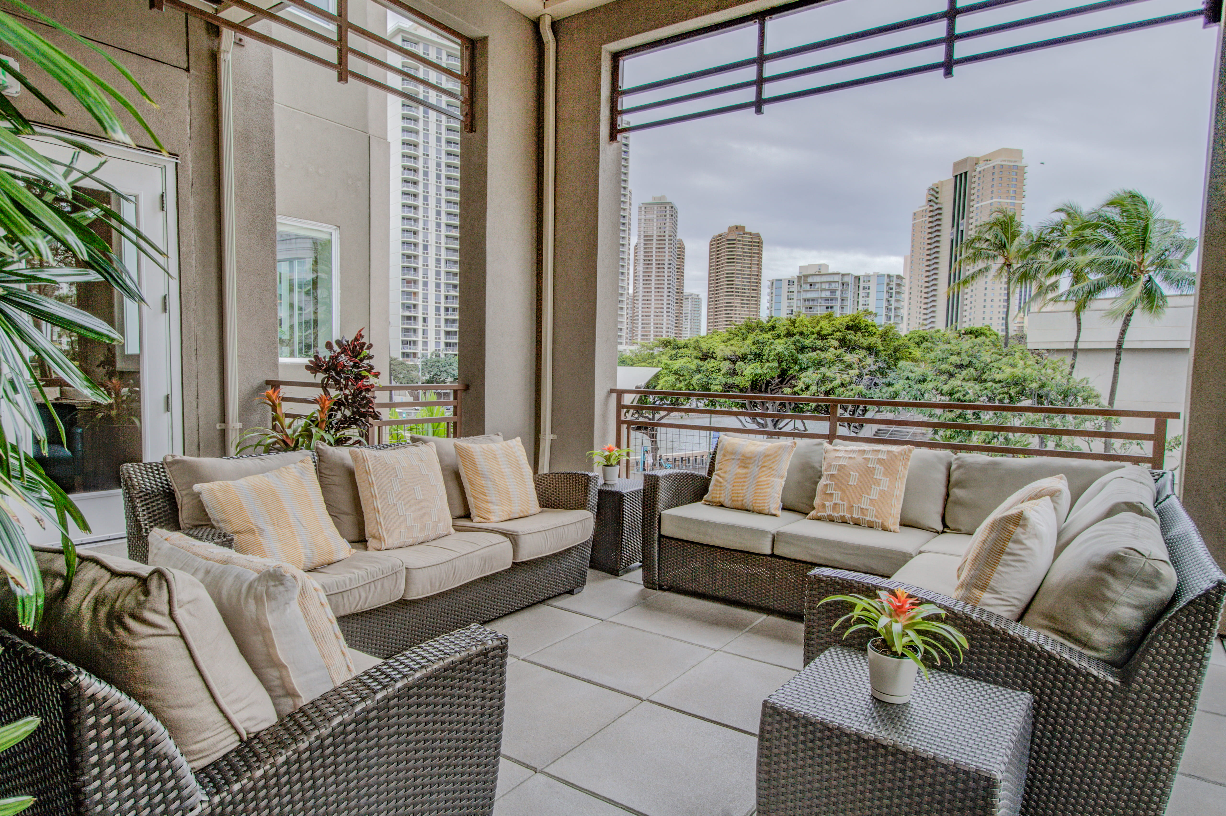 Covered outdoor lounge with wicker sofas and city skyline views at Waikiki.