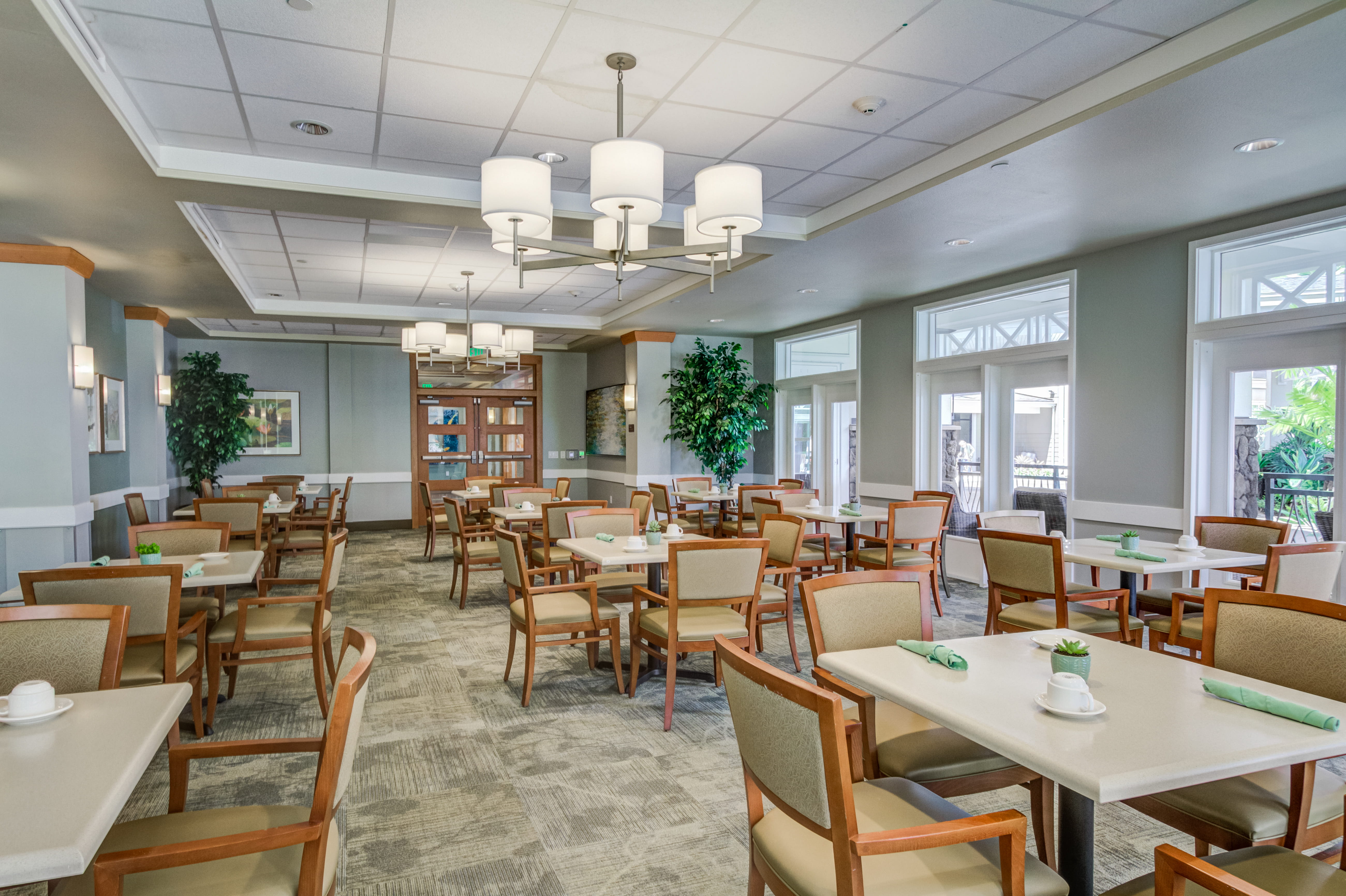 Elegant formal dining room with chandeliers at The Plaza Assisted Living.