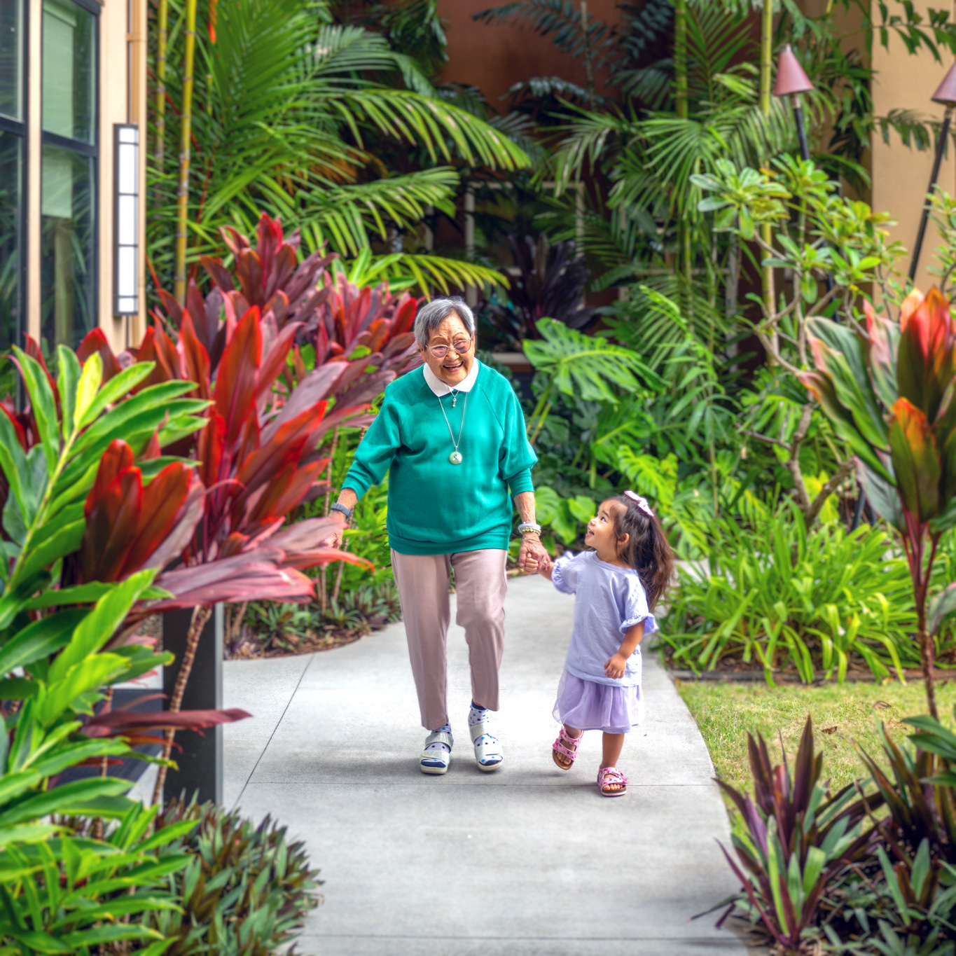 Senior woman walking with a young child in a courtyard at The Plaza Assisted Living.